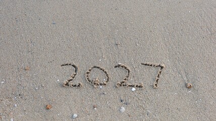 close up of year 2027 numbers written on the sand