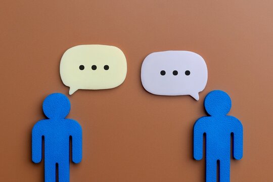 Two human-shaped icons facing each other with speech bubbles. Communication, dialogue, conversation, negotiation, public relations, and social interaction concept.