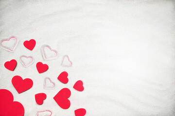 Creative sand texture with many wooden red hearts (big and small) and hearts drawing on the sand. Valentine's Day and love background. Empty place (pattern, card). Flat lay. Mockup.