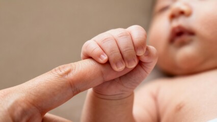 Baby's hand grasping adult's finger, symbol of love and connection