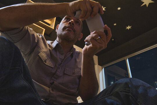 Man playing a video game holding a gray controller with stars on the ceiling above