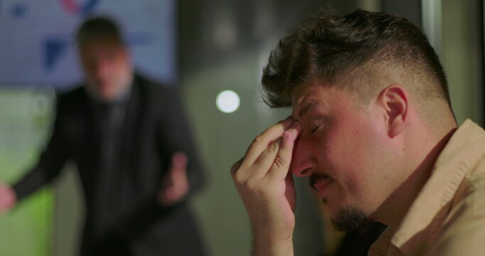 Furious manager confronting employees during heated office meeting as stressed team members react with anxiety and shame around conference table