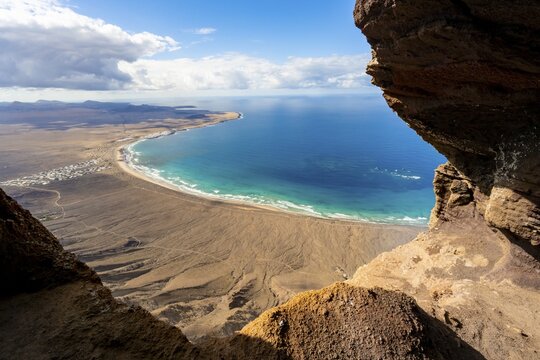 Cueva de las Cabras cave, view from the Risco de Famara cliffs on Famara beach, Playa de Famara with La Calaeta, Lanzarote, Canary Islands, Spain
