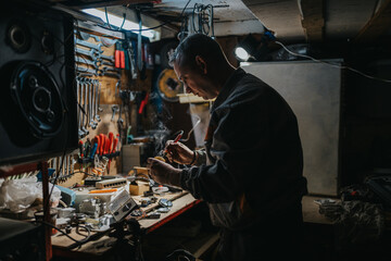 A focused technician in a dimly lit workshop carefully soldering small electronic components.