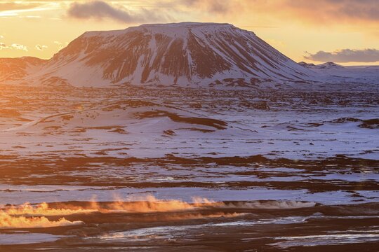 Hot springs and geothermal area in front of mountain landscape in winter, sunbeams, cloudy mood, Hverir, Namafjall, Myvatn, Iceland