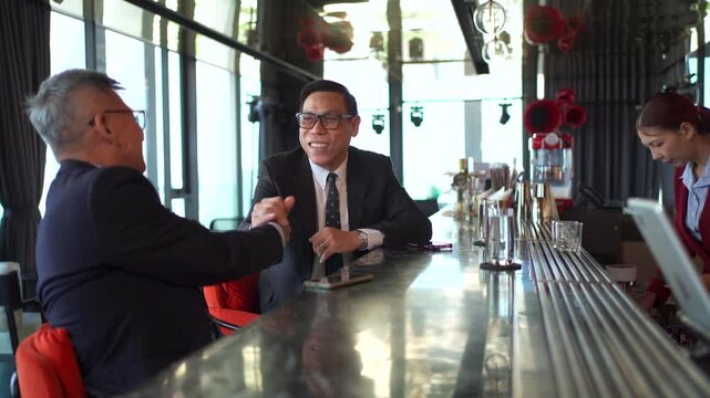 Businessmen shaking hands during a meeting at a modern luxury bar.