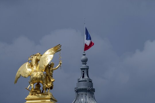Column with the group of figures Fama of Agriculture on the Pont Alexandre III bridge over the Seine, behind it the dome of the Grand Palais with the French national flag, Tricoloe, Paris, &Icirc;le-de-France, France