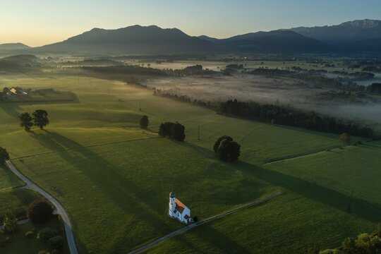 Aerial view of a chapel in front of mountains, morning light, Sankt Johannisrain, view of Zwiesel and Benediktenwand, Alpine foothills, Bavaria, Germany