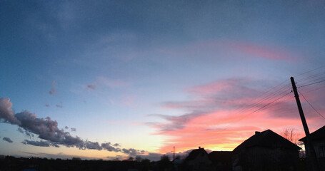 Amazing sunset view over the rural area with colorful pink yellow purple clouds on blue violet dark...