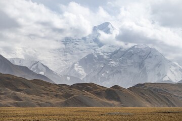 Glaciated, cloud-covered mountain peaks and golden meadows, Lenin Peak, Trans Alay Mountains, Pamir Mountains, Osh Province, Kyrgyzstan