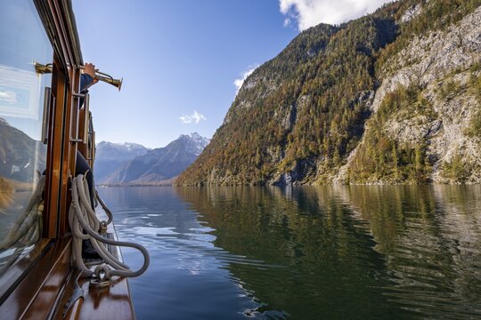 A trumpet is played on the echo wall of a tourist boat, K&ouml;nigssee, autumnal mountain landscape reflected in the lake, Berchtesgaden National Park, Berchtesgadener Land, Upper Bavaria, Bavaria, Germany