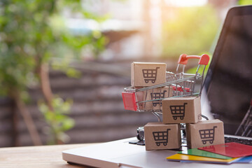 Shopping online. Credit card and cardboard box with a shopping cart logo in a trolley on laptop keyboard. Shopping service on The online web. offers home delivery