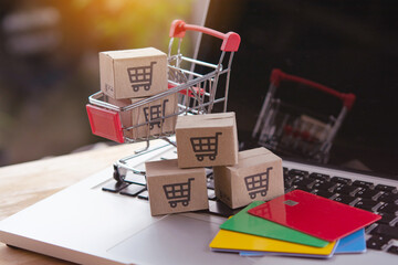 Shopping online. Credit card and cardboard box with a shopping cart logo in a trolley on laptop keyboard. Shopping service on The online web. offers home delivery