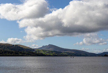 Two kayakers in distance on Bala Lake with distant hills and drifting clouds