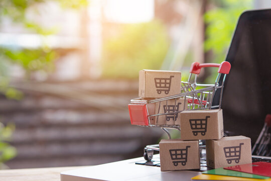 Shopping online. Credit card and cardboard box with a shopping cart logo in a trolley on laptop keyboard. Shopping service on The online web. offers home delivery