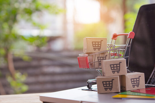 Shopping online. Credit card and cardboard box with a shopping cart logo in a trolley on laptop keyboard. Shopping service on The online web. offers home delivery - Powered by Adobe