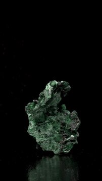 Malachite (green copper carbonate hydroxide) Fibrous chatoyant form giving cat's eye effect - rotating slowly against a black background. Vertical.