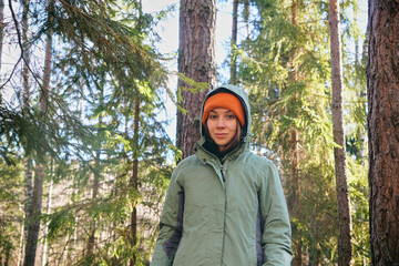 A young woman in bright clothes is standing in an autumn forest. Hiking in the forest on a sunny day