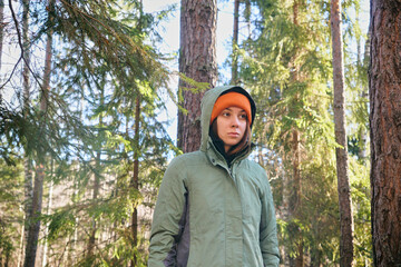A young woman in bright clothes is standing in an autumn forest. Hiking in the forest on a sunny day