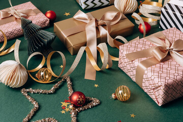 Colorful wrapped gifts with ribbons and ornaments arranged on a green background, creating a festive Christmas new year 2026 atmosphere for holiday celebrations