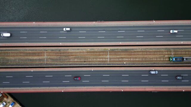 Top view of the road bridge over the river with moving cars. A city tram rides on rails. Aerial view. Multi-lane overpass. 4k footage