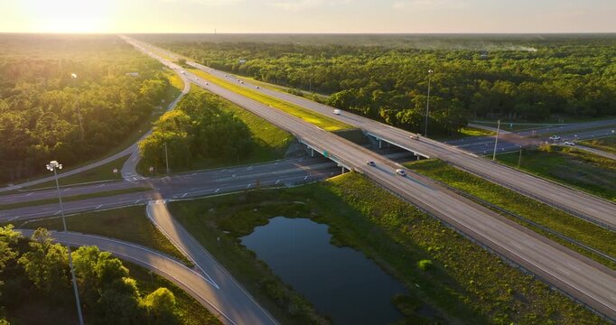 American highway bridge and exit lanes forming rural interchange with continuous vehicle movement at sunset