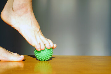 Toes gripping green massage ball demonstrating active foot muscle engagement during therapy session. Symbolizes toe strength development, intrinsic foot muscle activation, and balance training element