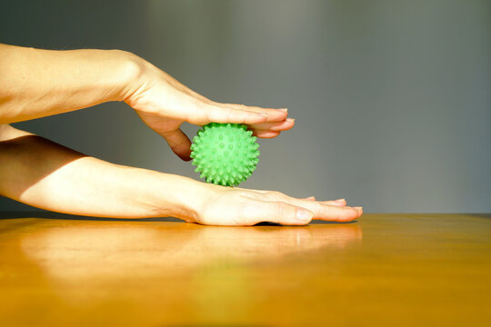 Female hands performing pressure massage with a textured therapy ball in natural light. Representing joint maintenance, repetitive strain prevention, mindful body awareness, and physical wellbeing.