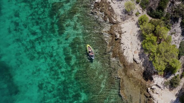 Rotating drone footage of Couple paddling yellow kayak floating by  Adriatic Sea waves. Aerial coastal top view footage.. Flying drone 4K footage. Active people traveling concept near Sibenik, Croatia