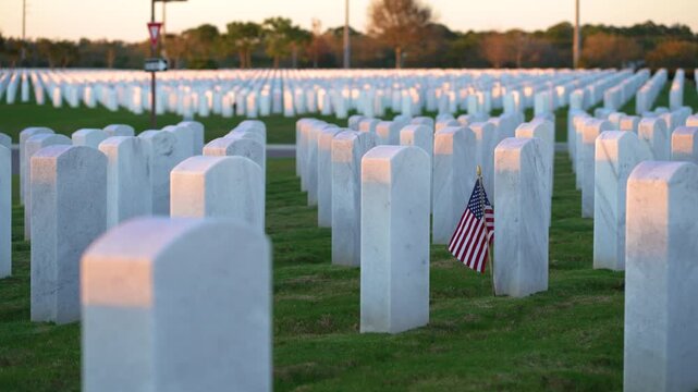 American national military cemetery with rows of white tomb stones and USA flag on green grass lawn. Memorial Day concept.