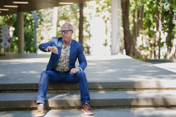 Mature man checking watch waiting outdoors on steps