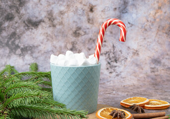 Hot drink in mug with small marshmallows and candy cane. Winter drinks, candy cane, spruce tree, oranges, anise stars. High quality photo