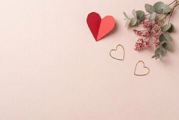 Paper heart and gold heart outlines with eucalyptus and pink flowers on pastel background, romantic flat lay for valentine greeting, wedding invitation or love celebration design