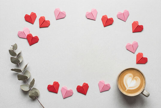 Heart latte and origami paper hearts arranged in a circle on light table, cozy coffee break with romantic flat lay composition for valentine greeting, love and celebration themes