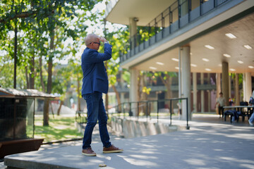 Mature man shading eyes looking up at modern building
