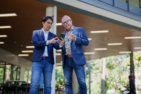 Colleagues discussing project on smartphone outdoors