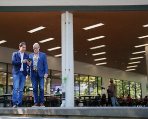 Businessmen discussing information on smartphone in modern setting