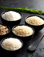 Black bowls of rice variations, a wooden spoon, and greens, all displayed on a textured, dark surface