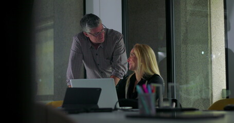 Male and female colleagues reviewing work together on laptop in modern office meeting room during collaborative session
