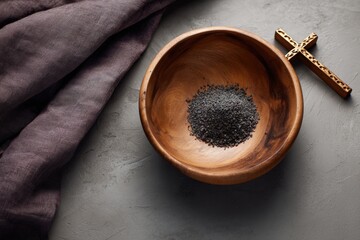 Wooden bowl with ashes and cross on gray surface for ash wednesday observance
