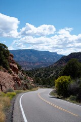 Fototapeta premium Winding road through scenic mountain landscape under blue sky