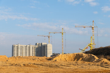 Several tower cranes stand tall over a large new high-rise residential development