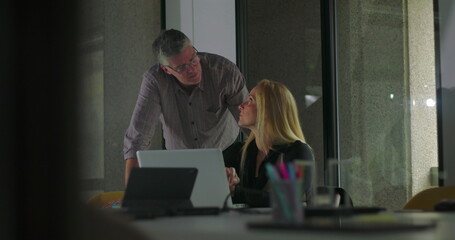 Male colleague pointing at screen while blonde businesswoman listens and engages during collaborative work session in office meeting room