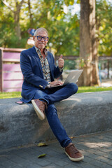 Obraz premium Mature man freelancing on laptop giving thumbs up gesture