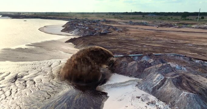 Phosphate mining site in Florida with large pipe ejecting water and sand slurry during mineral extraction process.