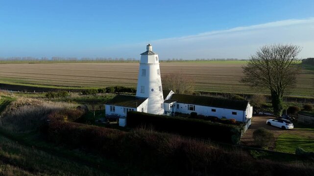 Cinematic aerial drone sweep approaching the historic Sir Peter Scott East Lighthouse beside the River Nene, revealing tidal wetlands and rural Lincolnshire landscapes.