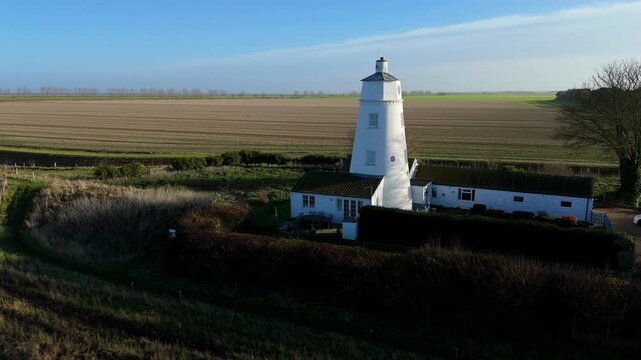 Cinematic aerial drone sweep approaching the historic Sir Peter Scott East Lighthouse beside the River Nene, revealing tidal wetlands and rural Lincolnshire landscapes.