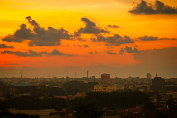 Fototapeta premium Orange and red sunset clouds over the city skyline at dusk