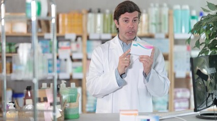 In sales area of pharmacy, man consultant sells intestinal probiotic. Healthcare worker advertises safe remedy for symptom relief.