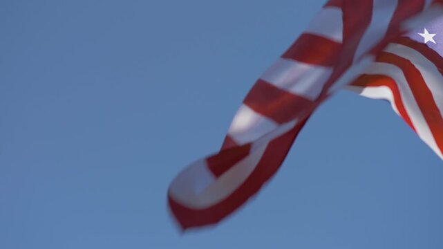 The American flag stands tall in clear blue sky, its bold colours shining bright. It symbolises ideals of justice, liberty, equality, reminding us of the sacrifices made for the freedoms we cherish